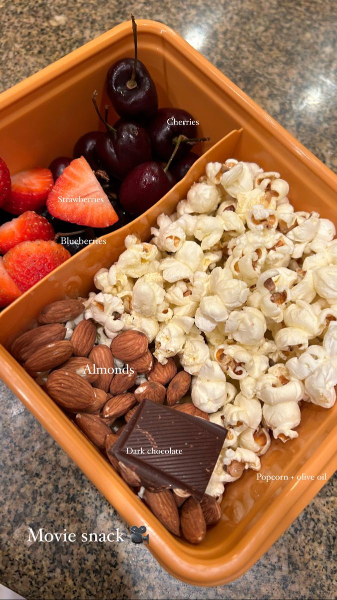 an orange container filled with fruit and nuts next to a bowl of chocolate covered strawberries