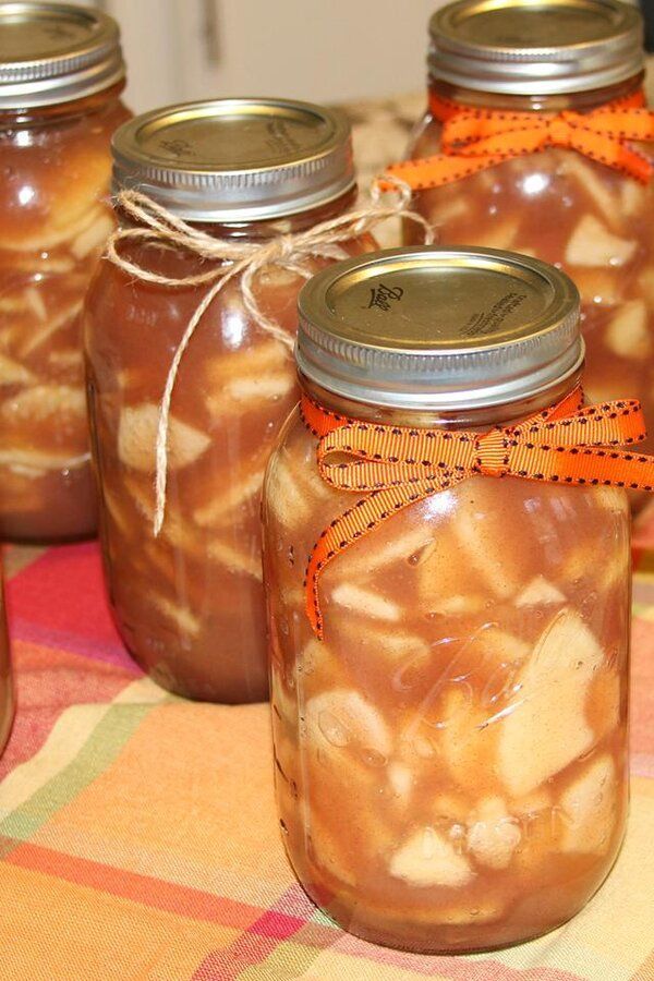 several jars filled with apple pie fillings sitting on a checkered tablecloth covered table