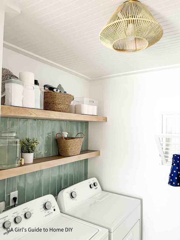 a washer and dryer in a small room with open shelves on the wall