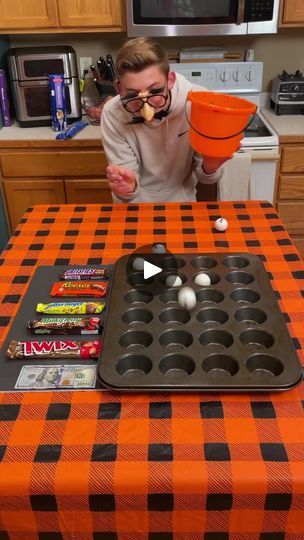 a man with an orange and black table cloth is making cupcakes in the kitchen