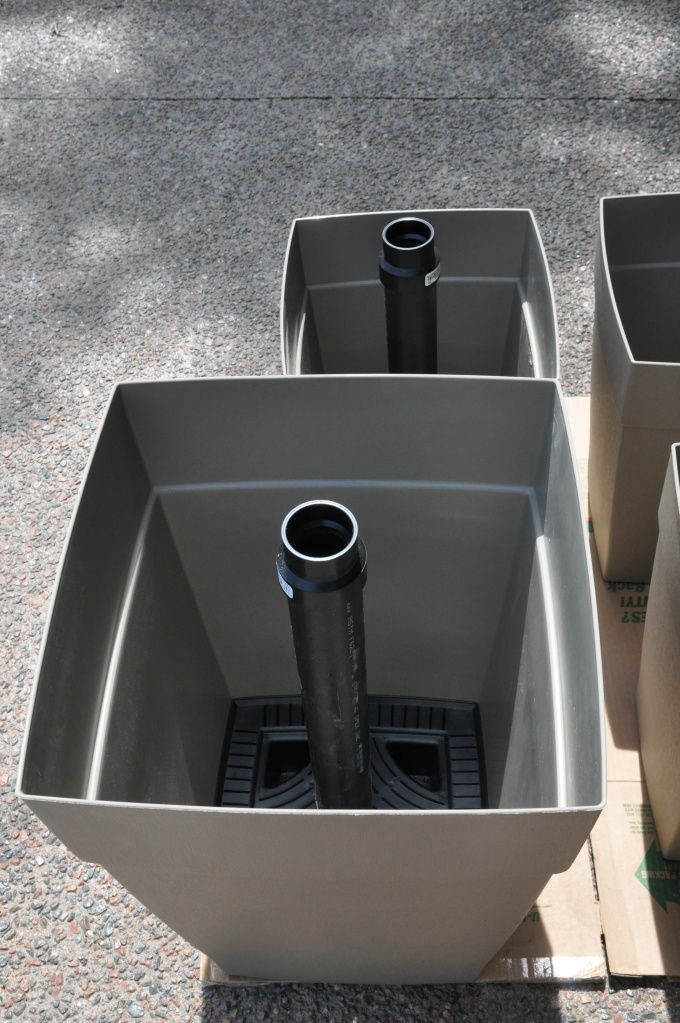 three large gray containers with black handles on the ground