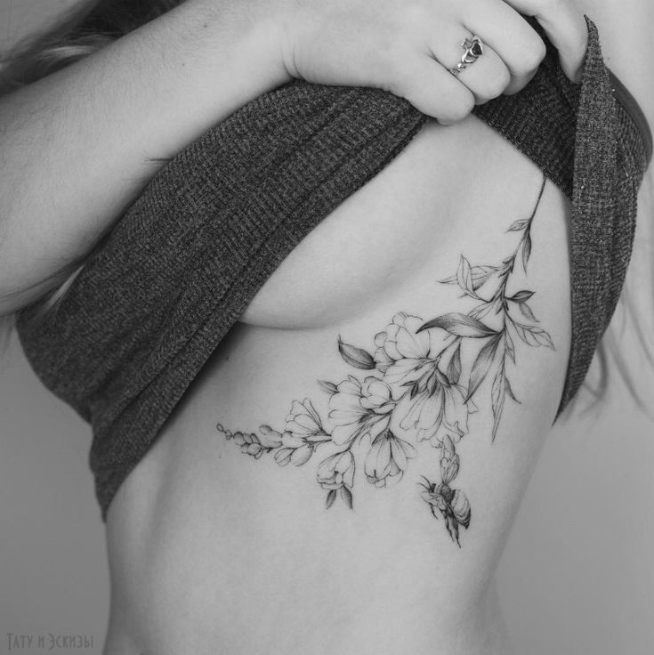 a black and white photo of a woman's stomach with flowers on the side