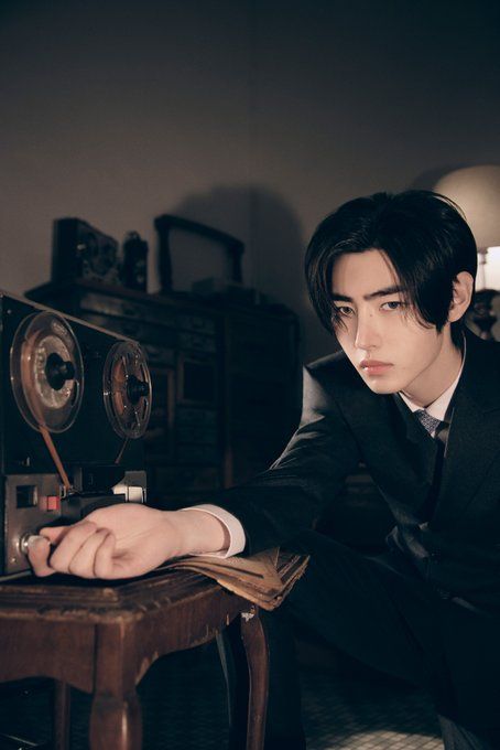 a man in a suit sitting on a chair next to an old fashioned radio and record player