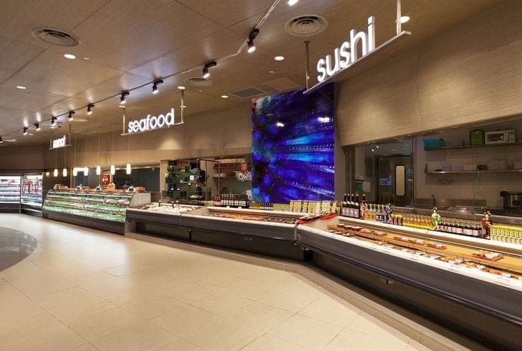 the inside of a food court with many items on display and people walking around it