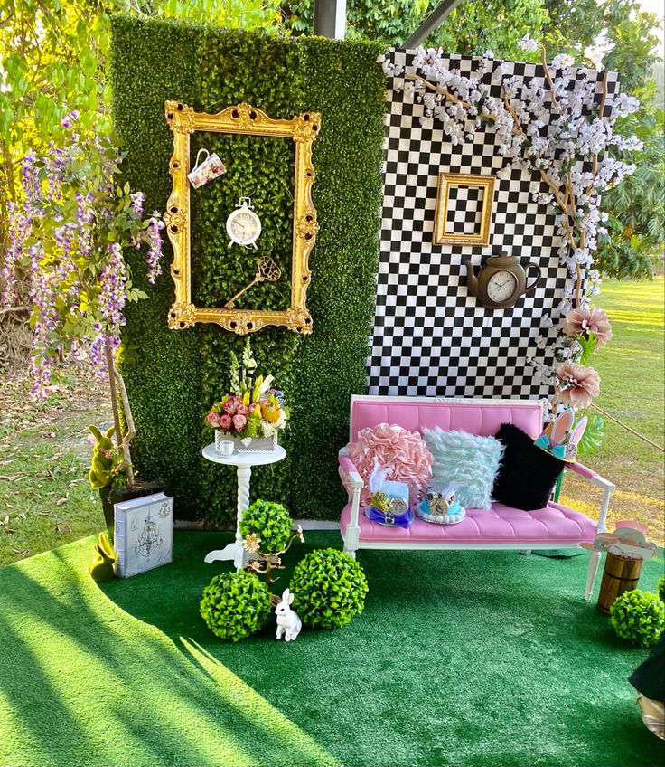 a couch sitting on top of a lush green field next to a wall covered in flowers