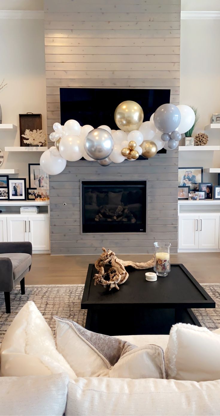 a living room filled with white furniture and balloons on the wall above the fire place