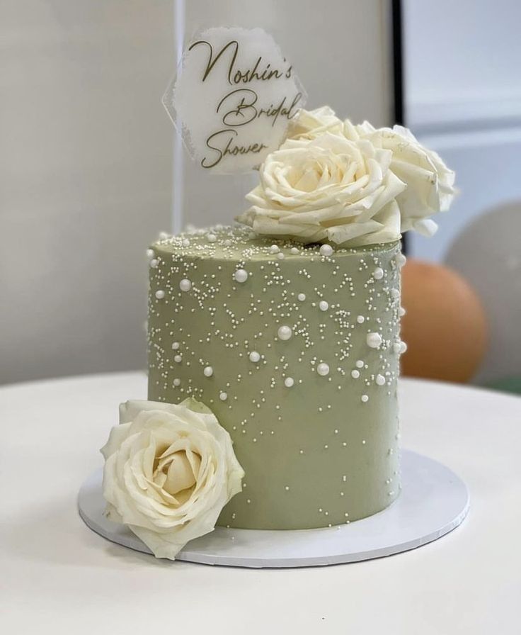 there is a green cake with white flowers on it