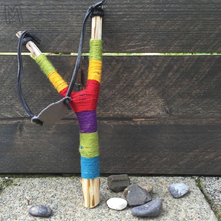 a colorful crocheted stick is on the ground next to some rocks and stones