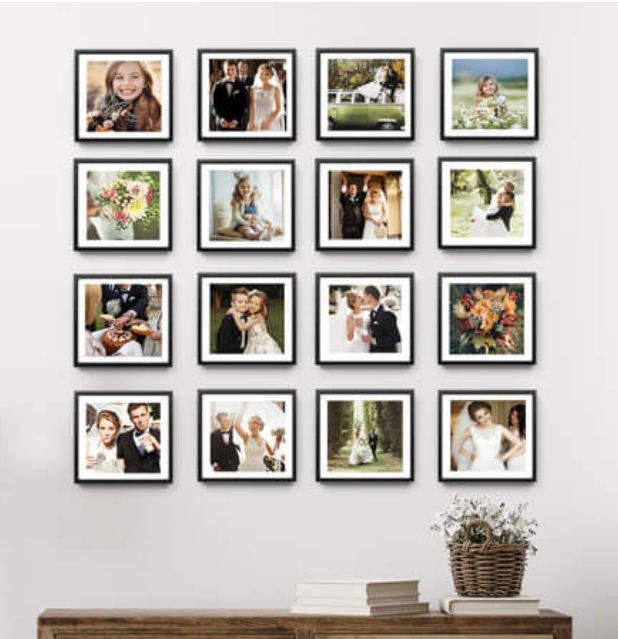 a bunch of pictures are hanging on the wall above a table with a basket full of flowers