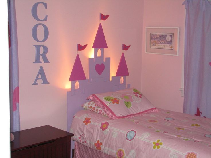 a bedroom decorated in pink and purple with princess castle decorations on the wall above the bed