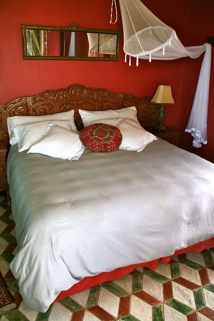 a bed in a bedroom with red walls and white bedspread on top of it