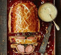 a meat loaf with sauce on the side and a knife next to it, sitting on a red tray