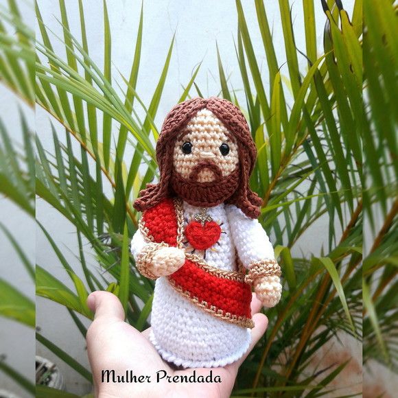 a small crocheted jesus doll is shown in front of some palm tree leaves