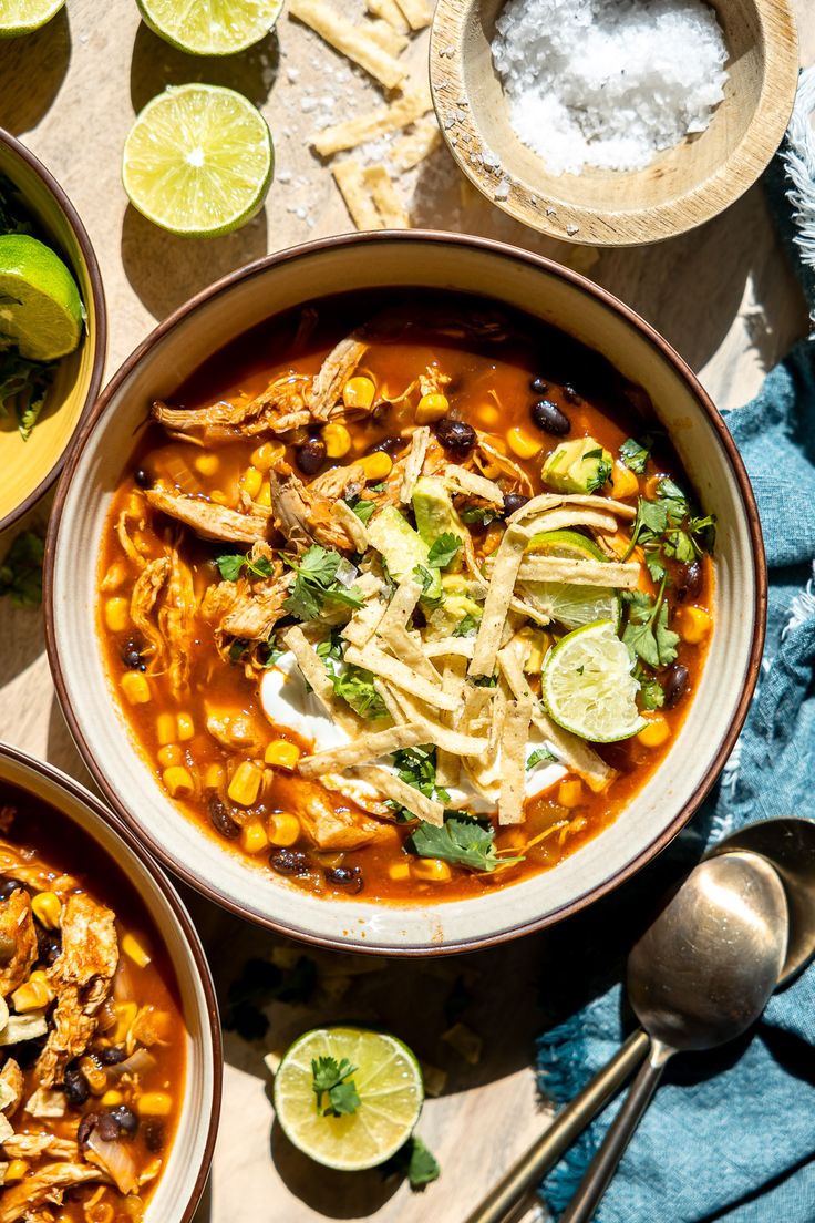 two bowls of mexican chicken tortilla soup with limes and cilantro