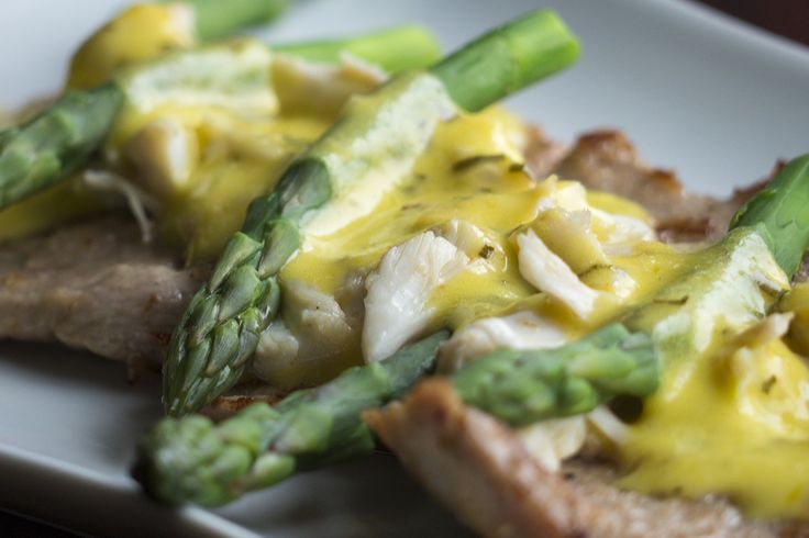 asparagus and cheese on bread with sauce on it sitting on a white plate