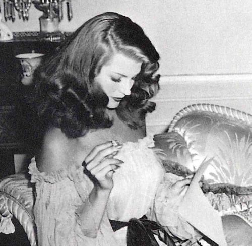 a black and white photo of a woman sitting on a couch looking at something in her hand