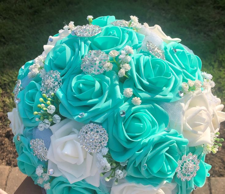 a bridal bouquet made up of blue and white roses with crystal brooches