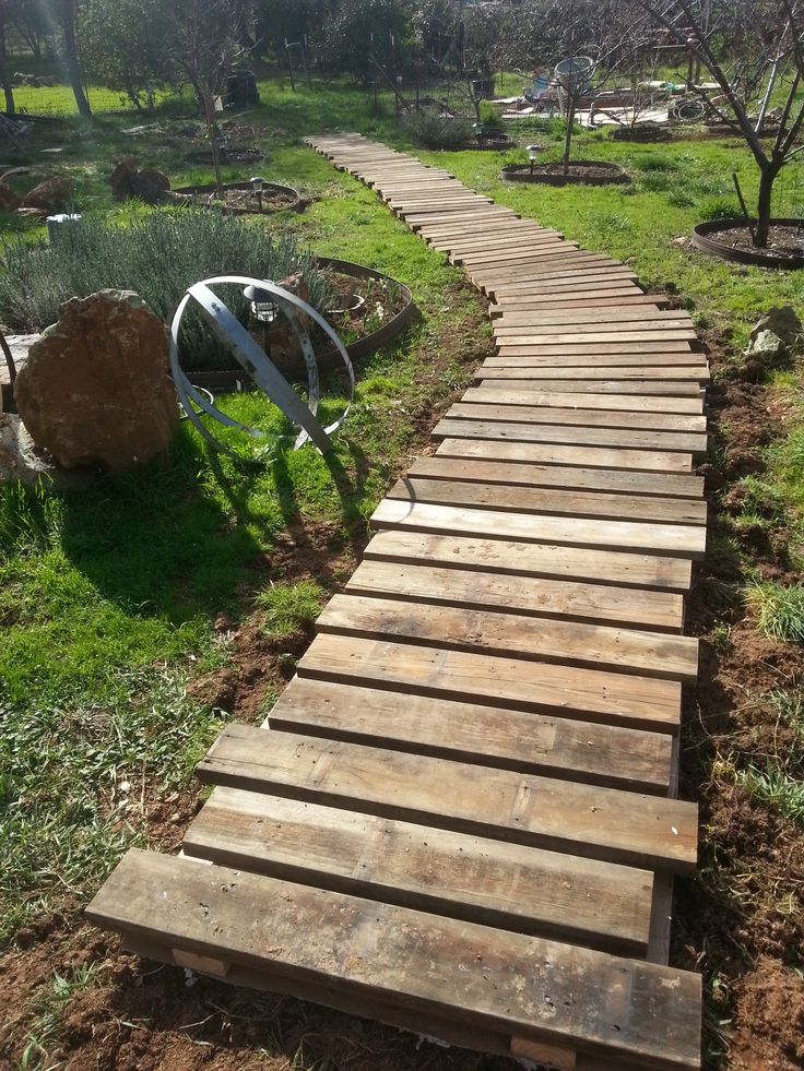 a wooden walkway in the middle of a garden