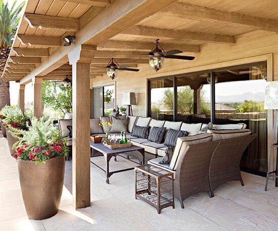 an outdoor living area with couches, tables and potted plants on the patio