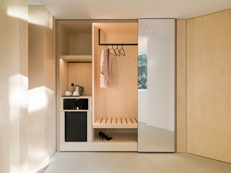 an open closet with clothes hanging on the wall and shoes sitting on the shelf next to it