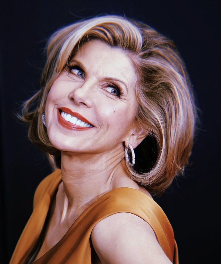 a close up of a person with a smile on her face and wearing an orange dress