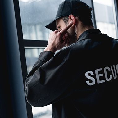 a security man standing in front of a window with his hand on his face and looking out the window