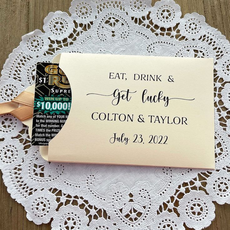 a wedding guest book on a doily next to a tag with the words eat, drink and get lucky written on it