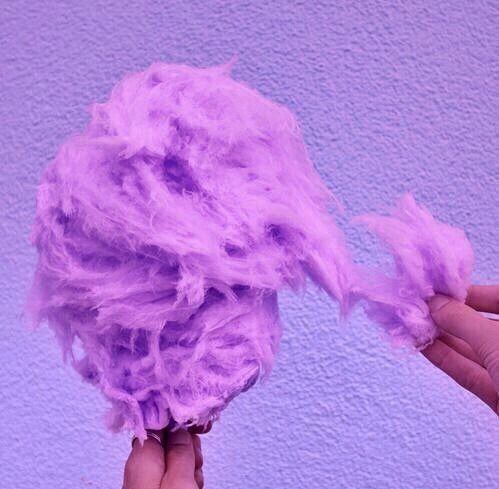 someone is holding a purple ball of yarn in front of a blue and white wall