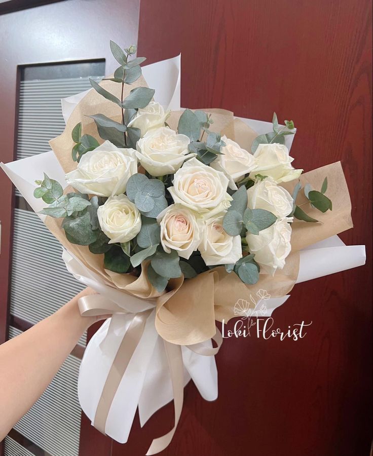 a bouquet of white roses is being held by someone