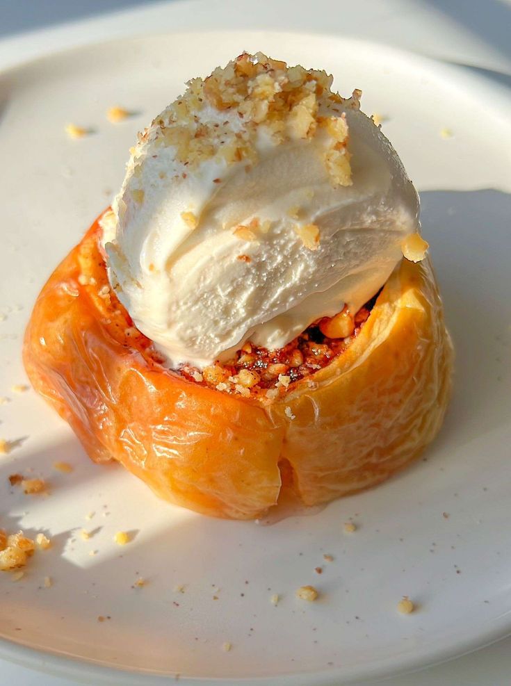 a white plate topped with an orange covered in ice cream and toppings on top of it