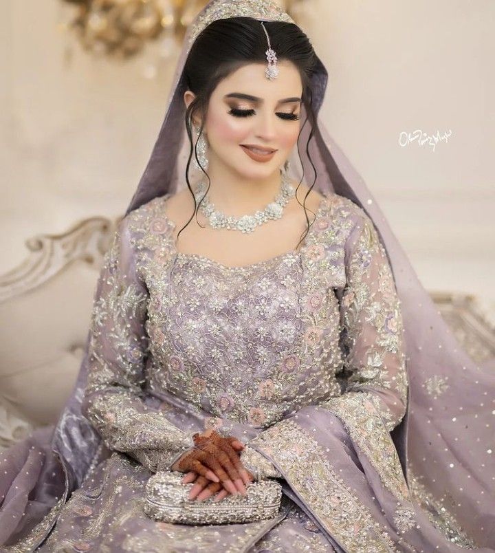 a woman in a purple wedding dress sitting on a white couch wearing a tiara