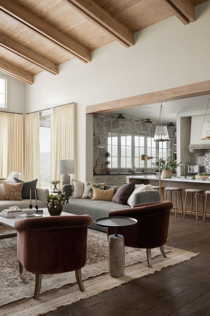 a living room filled with furniture and lots of windows next to a stone wall covered in wood