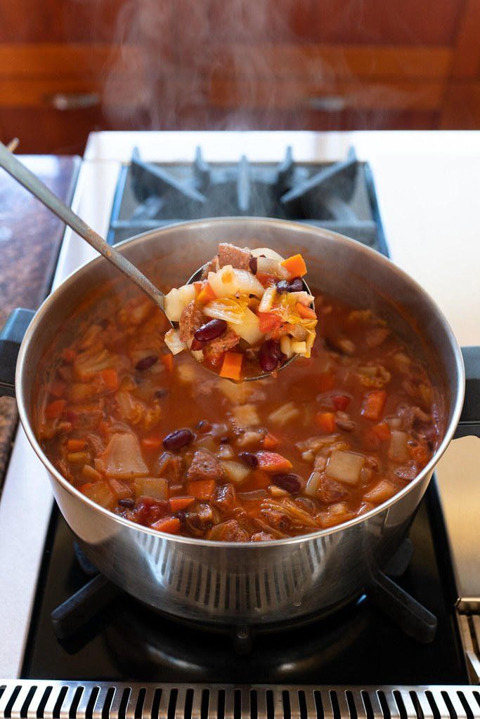 a pot filled with soup sitting on top of a stove next to a burner