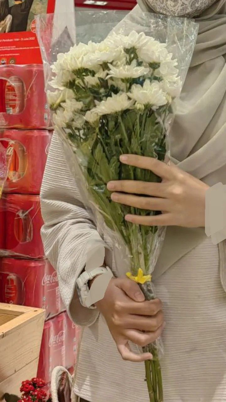 a woman holding a bouquet of flowers in front of a store display case with red boxes