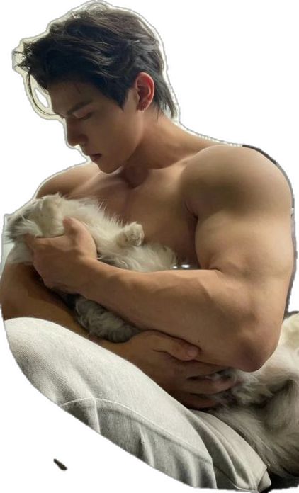 a shirtless man holding a small white dog