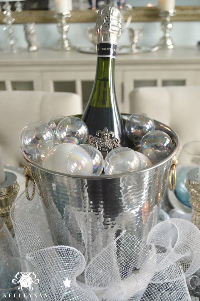 a bottle of champagne sitting in a bucket filled with glass balls on top of a table