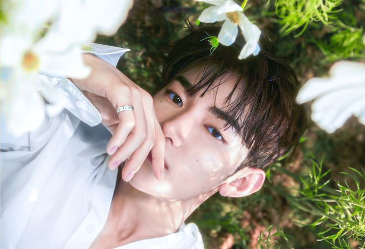 a young man is posing for a photo with flowers in his hair and wearing a white shirt