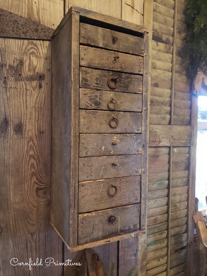 an old chest of drawers is hanging on the wall