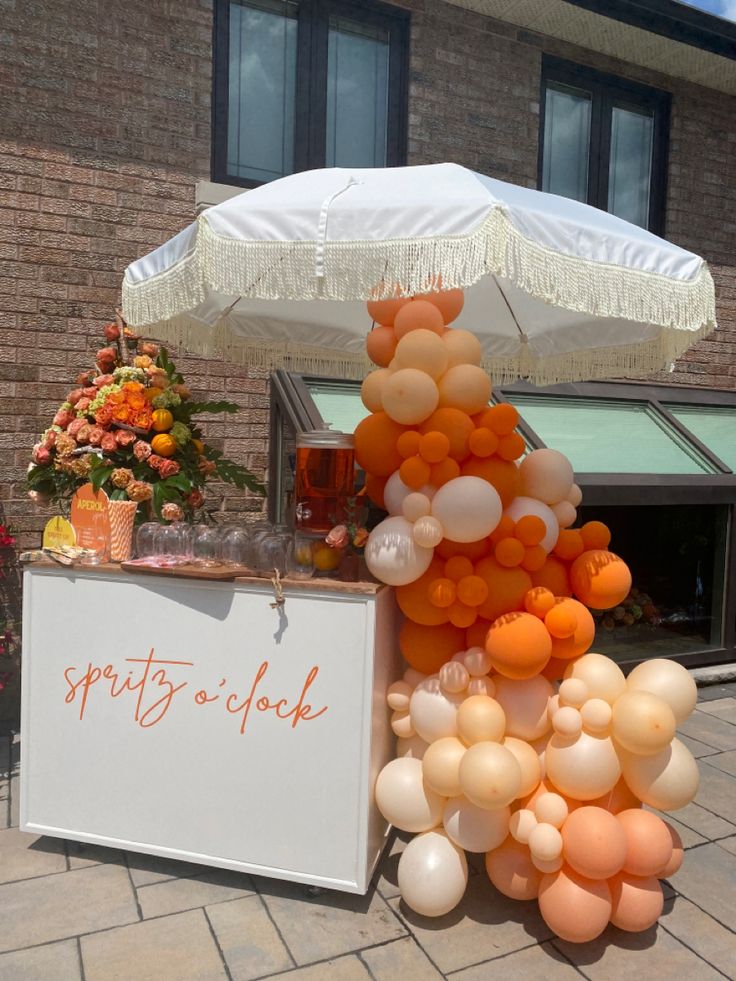 an umbrella and some balloons on the side of a building with a sign that says spirit's o clock