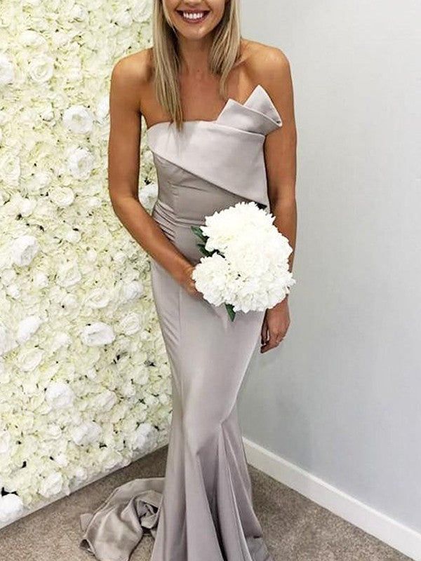 a woman standing in front of a flower wall holding a bouquet and smiling at the camera