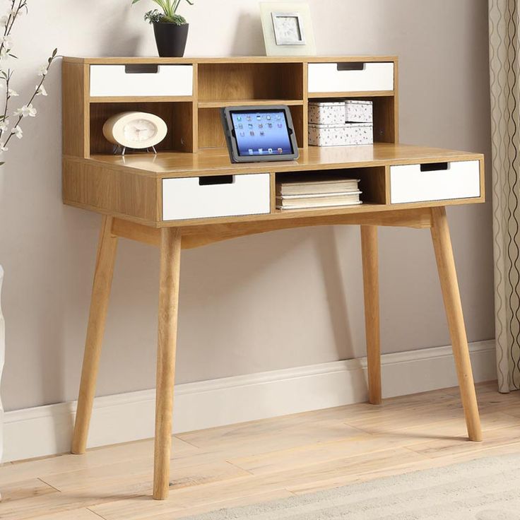 a wooden desk with drawers and pictures on the wall above it, along with a vase filled with flowers