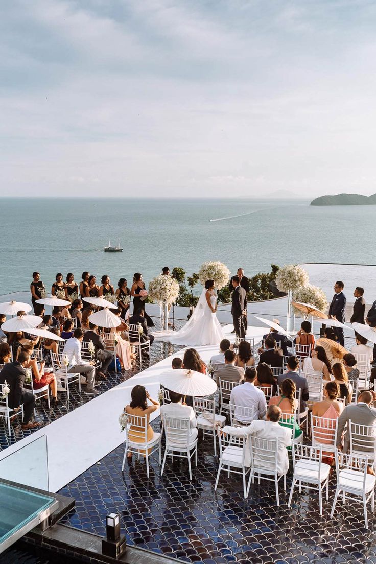 an outdoor wedding ceremony on the roof of a building overlooking the ocean with umbrellas