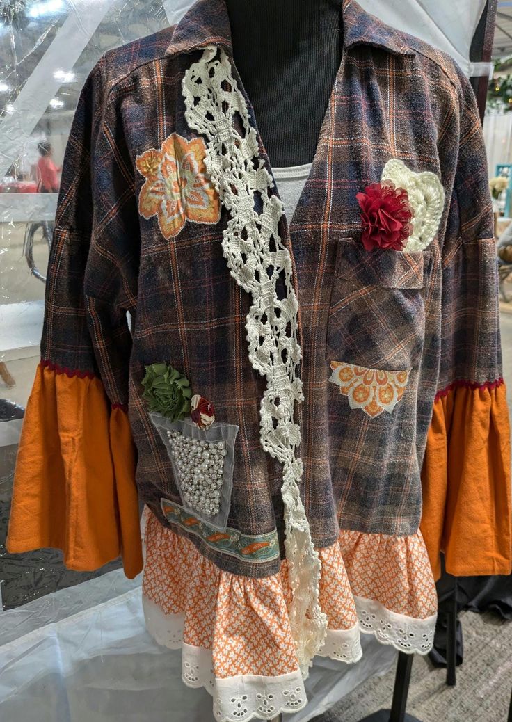 a mannequin wearing an orange and brown jacket with flowers on it's chest