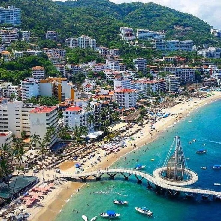 an aerial view of a beach with boats in the water and buildings on the shore