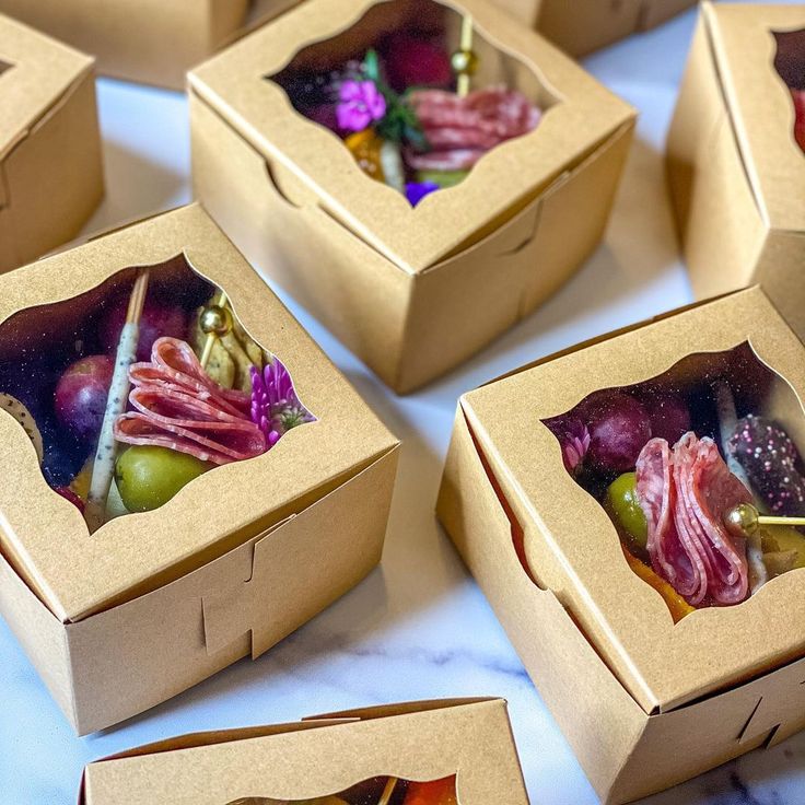 several boxes filled with different types of food on top of a white tablecloth covered table