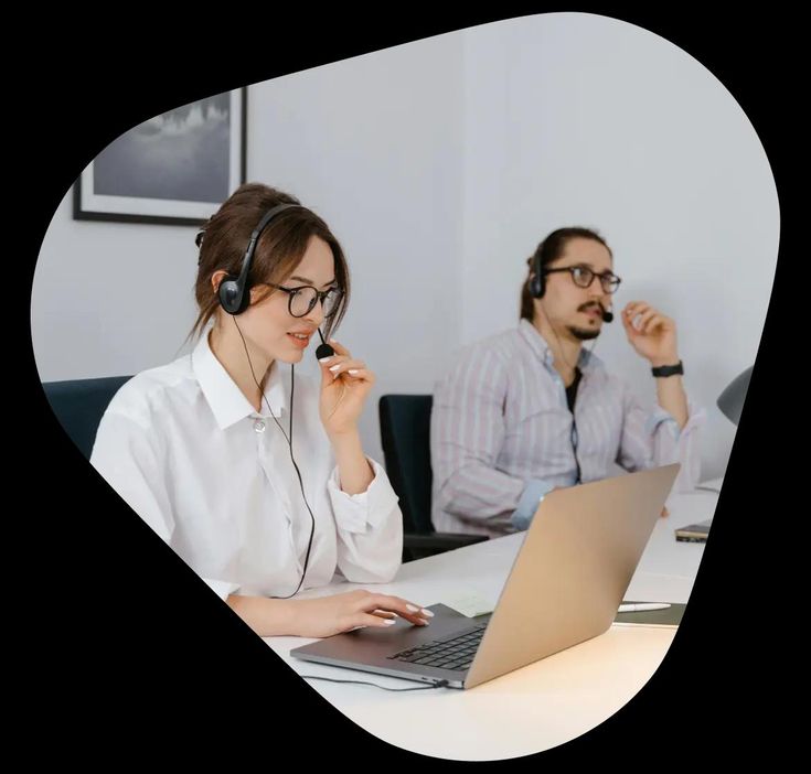 two people sitting at a table with laptops and headphones on their headsets