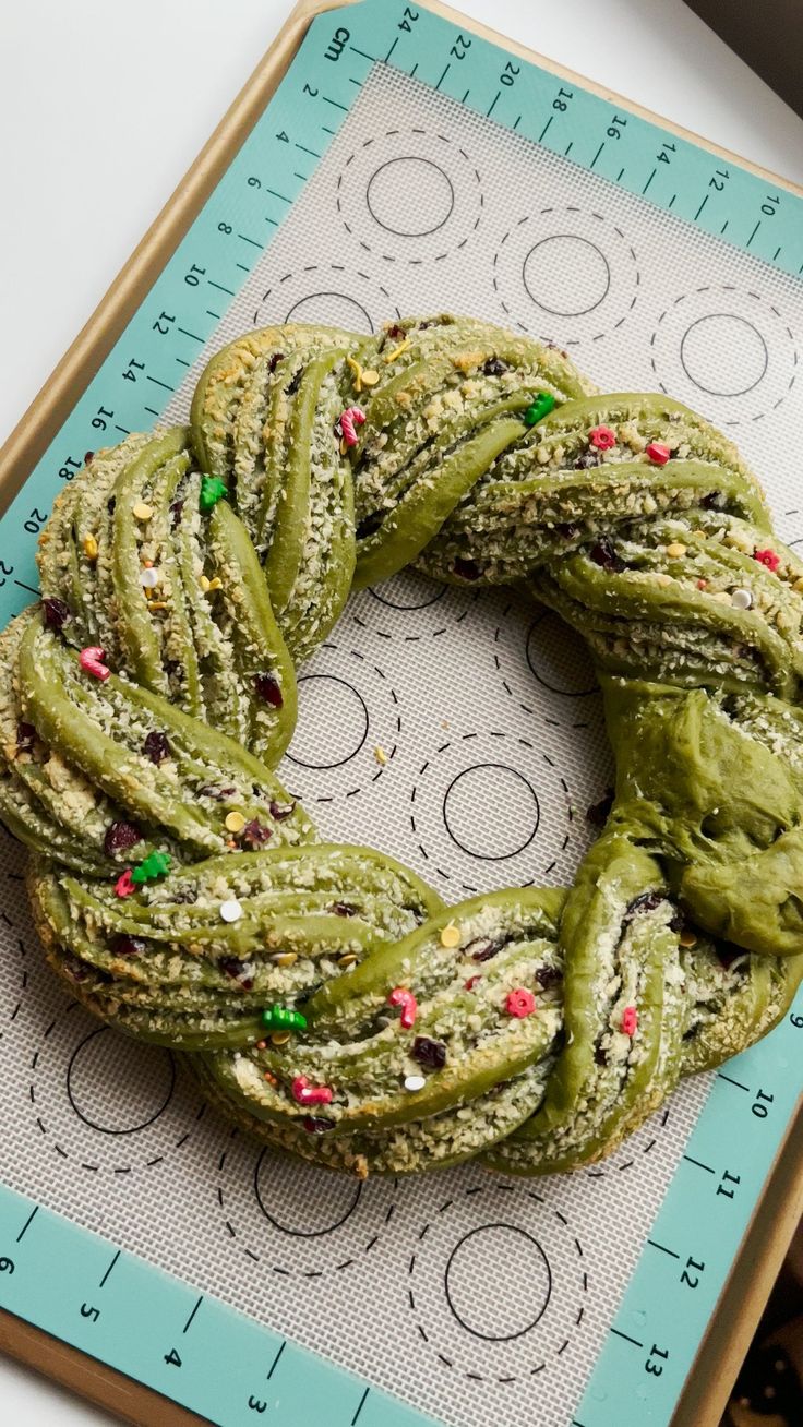 a green doughnut with sprinkles on top of a cookie sheet in front of a ruler