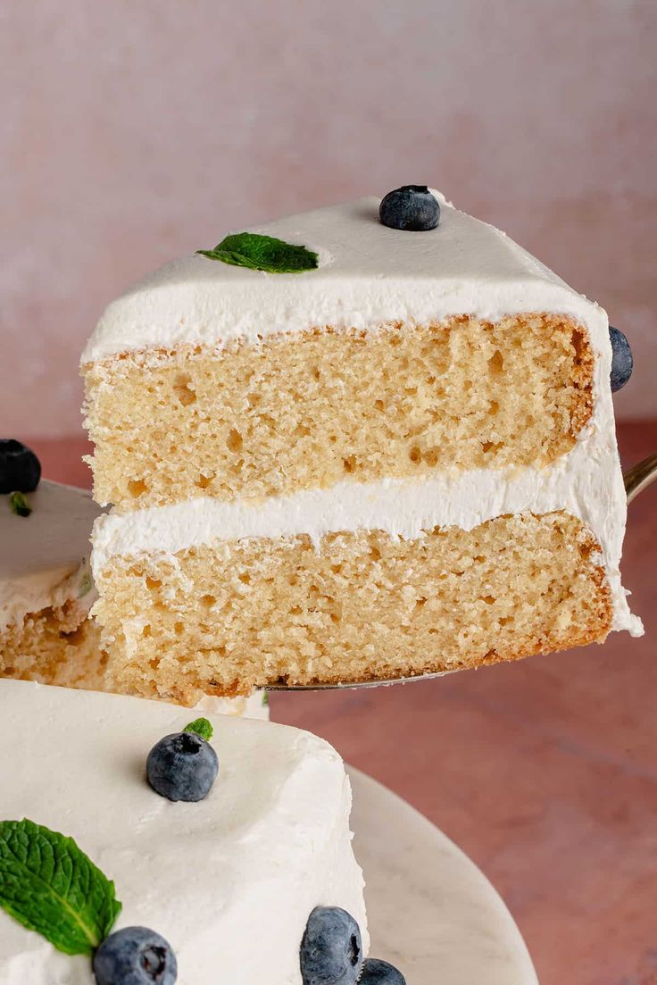 a slice of cake with white frosting and blueberries