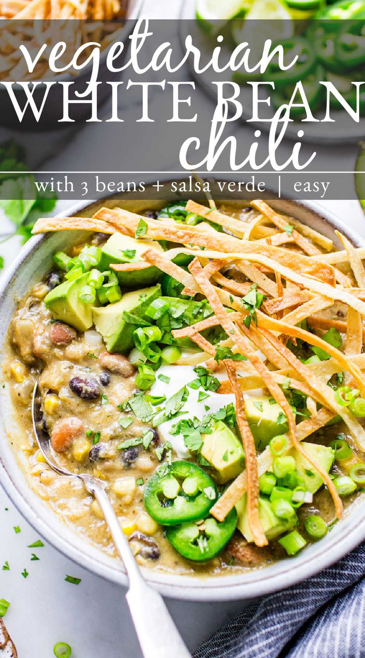 vegetarian white bean chili in a bowl with shredded cheese and avocado on the side