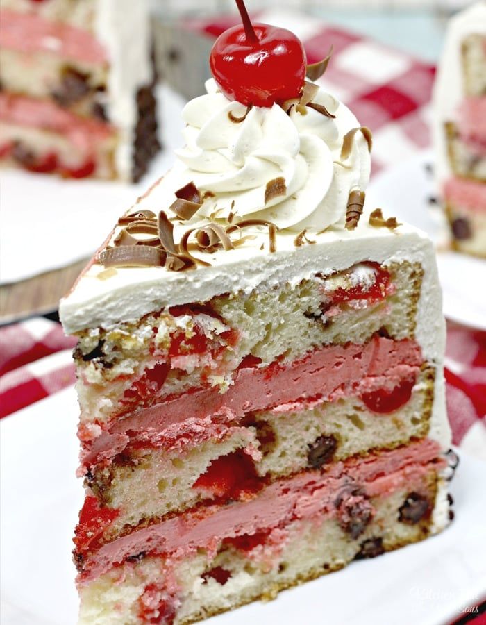 a slice of cake with white frosting and cherries on top